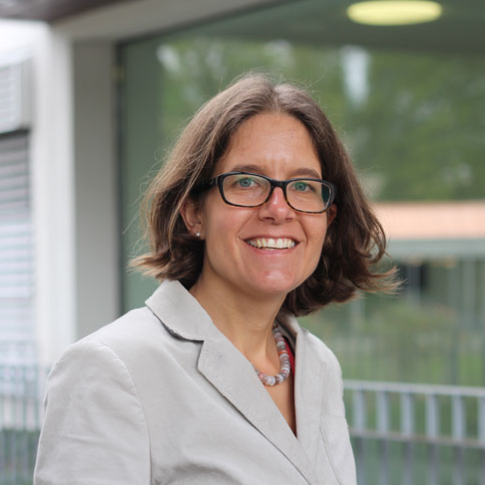 Portrait Salomé LeibundGut, weiblich lesbare, weisse Person mit mittellangen Haaren, Brille, Ohrsteckern, Halskette und grauem Blazer
