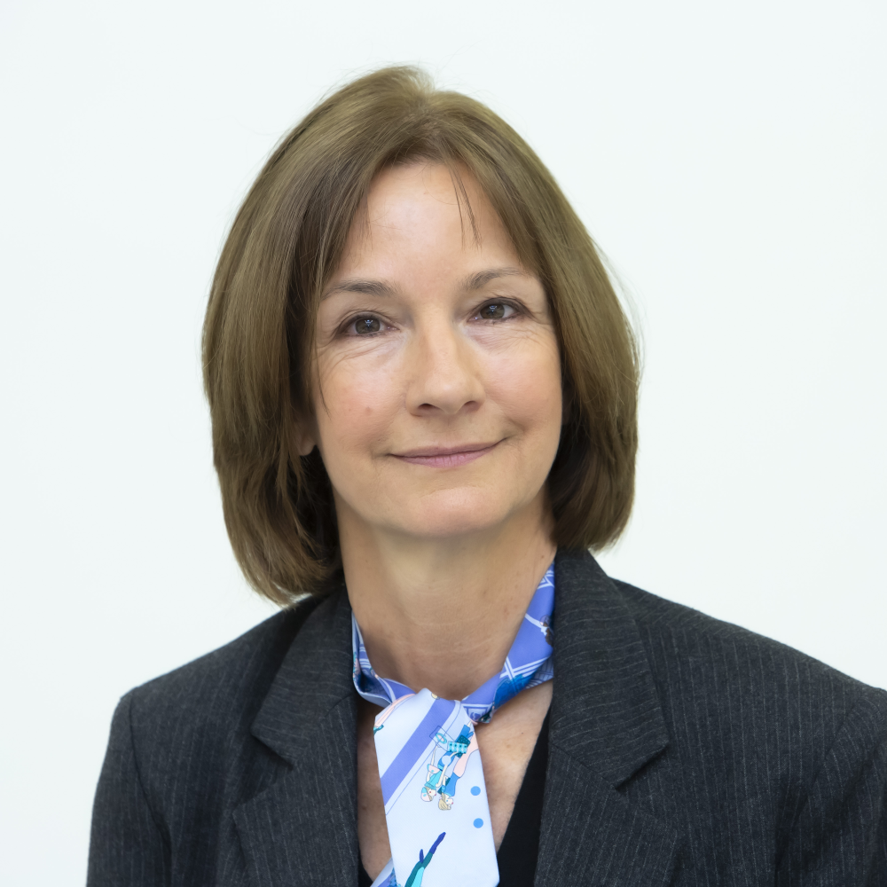 Portrait Prof. Dr. Katja Langenbucher, Person mit mittellangen, hellbraunen Haaren, blau-gemustertem Schal, schwarzem Oberteil und schwarzem Nadelstreifen-Blazer