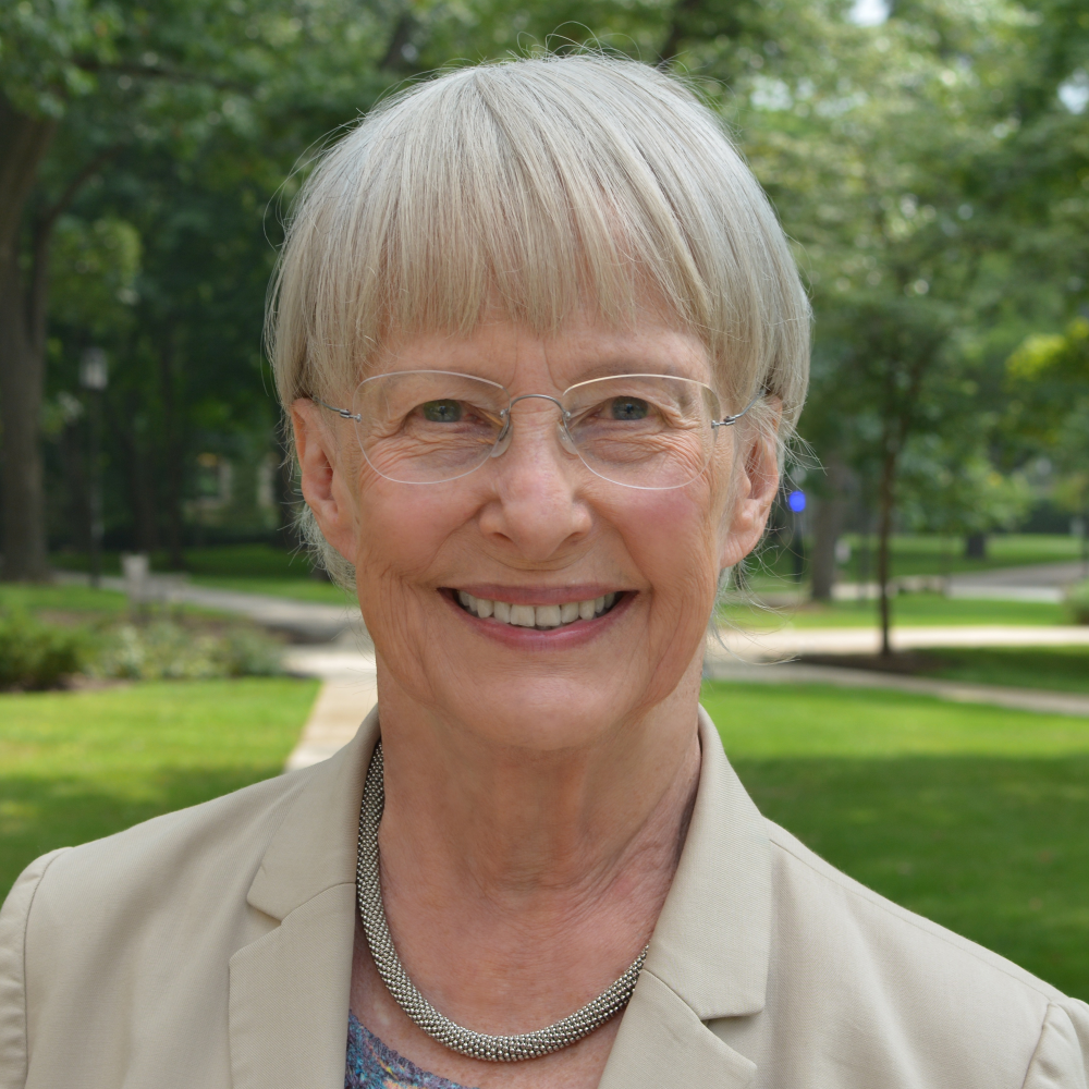 Portrait Alice Eagly, weiblich lesbare, weisse Person mit kurzen Haaren, Brille, Kette und beigem Blazer